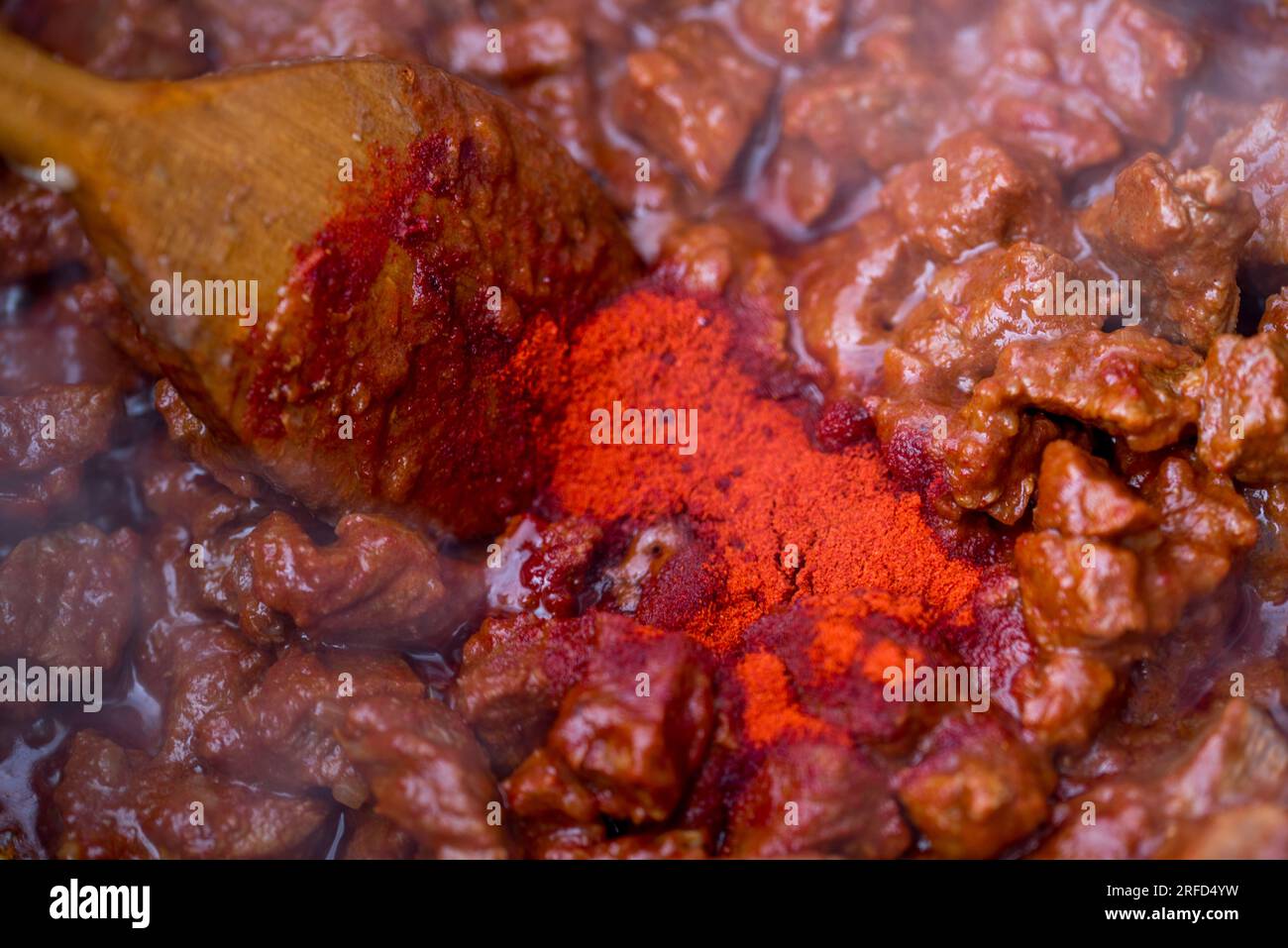 traditional hungarian goulash is boiling in a cauldron. Stock Photo