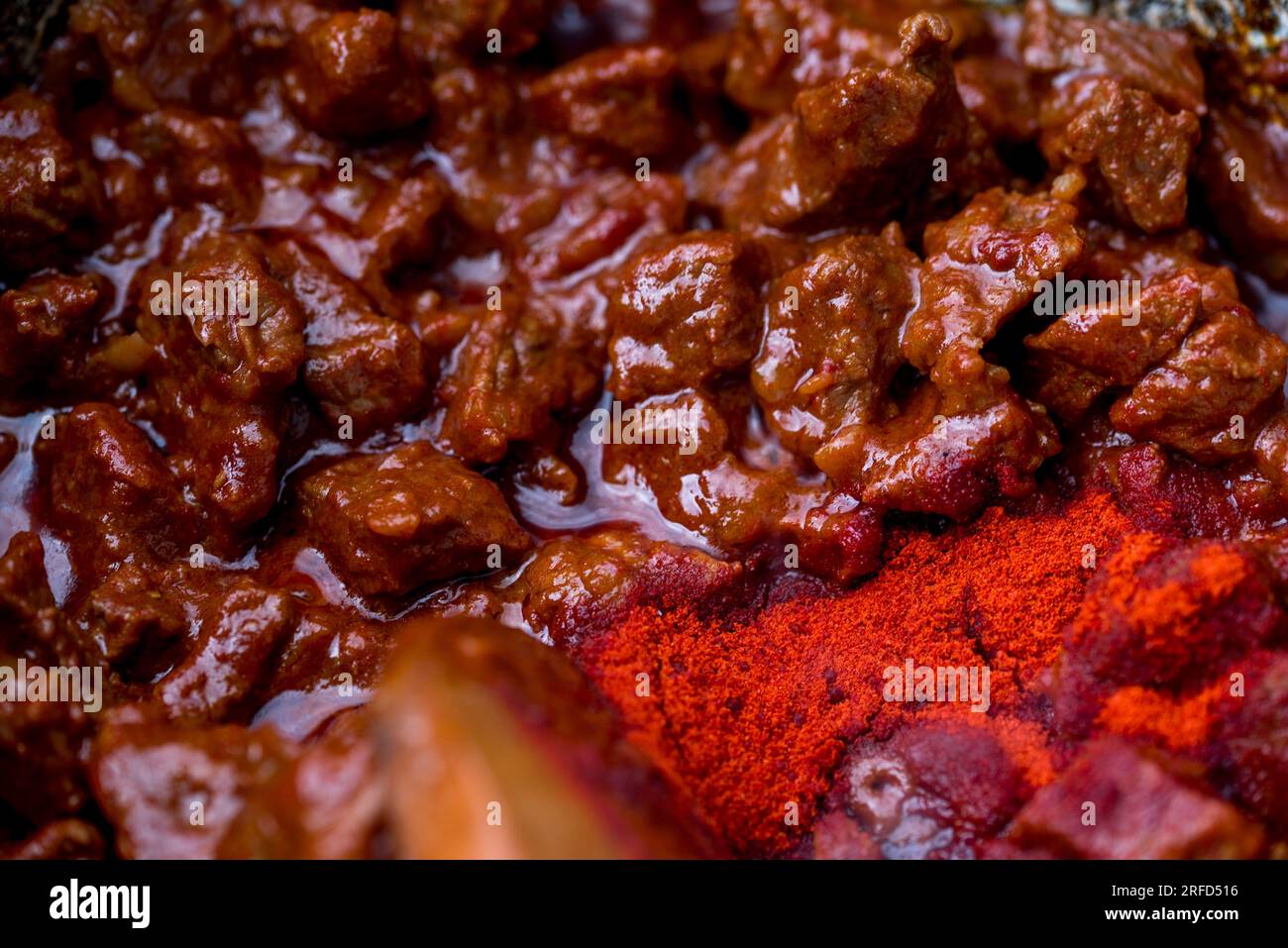 traditional hungarian goulash is boiling in a cauldron. Stock Photo