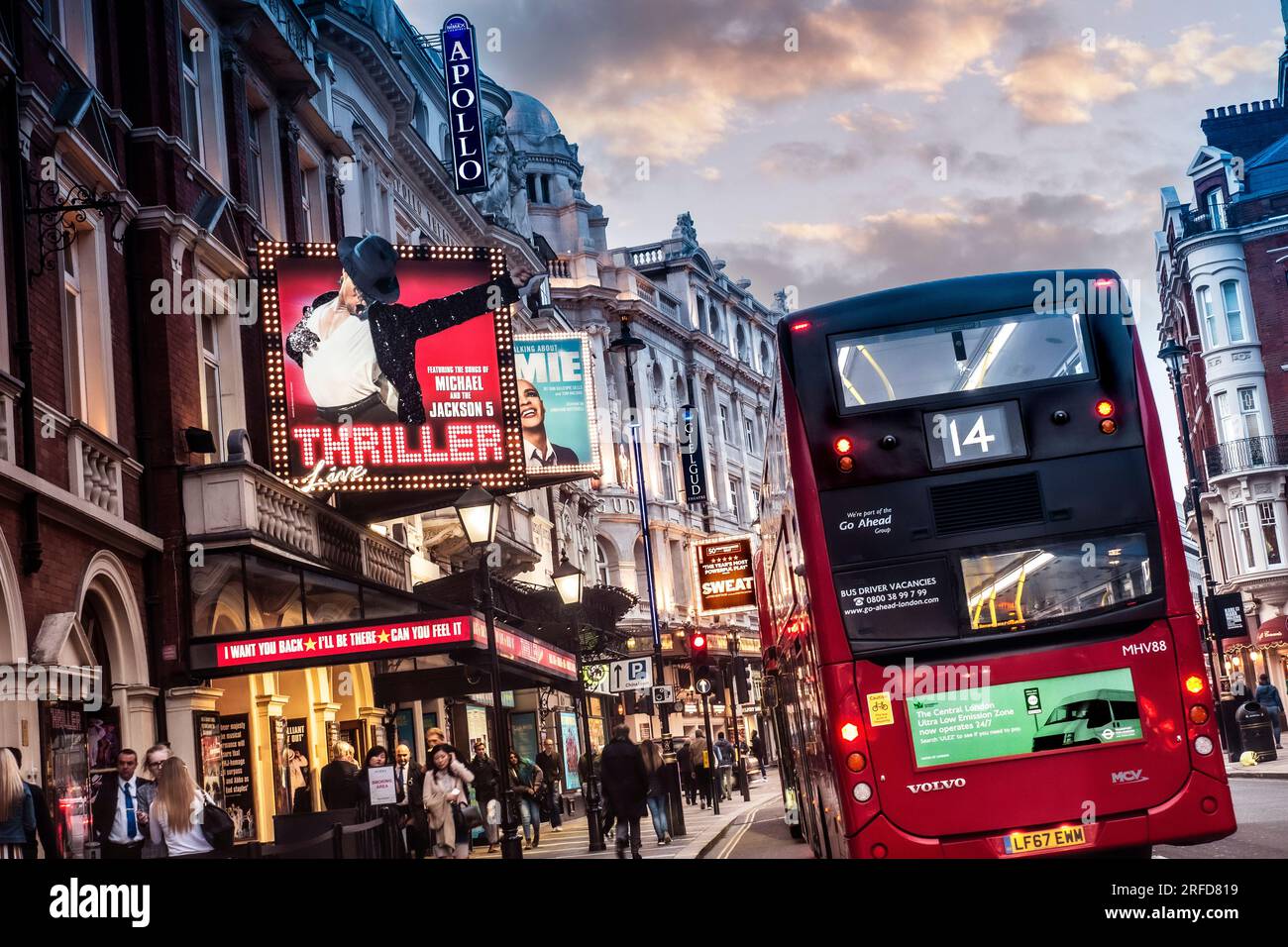 LONDON ULEZ  2019 RETRO ADVERTISEMENT RED BUS SHAFTESBURY AVENUE NIGHT LONDON TRAFFIC SUNSET  Theatreland West End Apollo & The Gielgud theatres busy heavy pollution diesel fumes Shaftesbury Avenue at dusk West End London UK Stock Photo