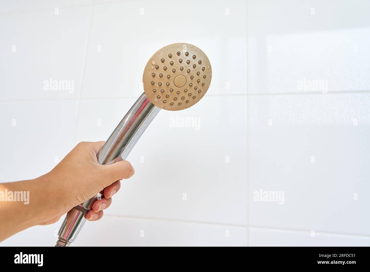 Woman holding in hand corroded limescale calcified old shower head