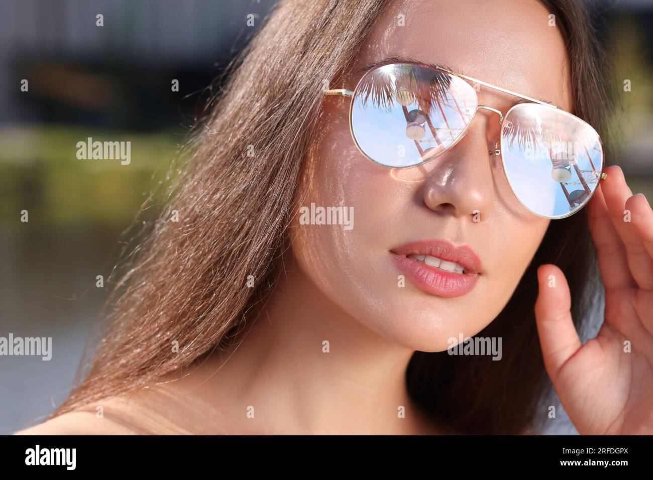 Beautiful woman in sunglasses on sunny day outdoors. Sky, palm tree and observation wheel reflecting in lenses Stock Photo