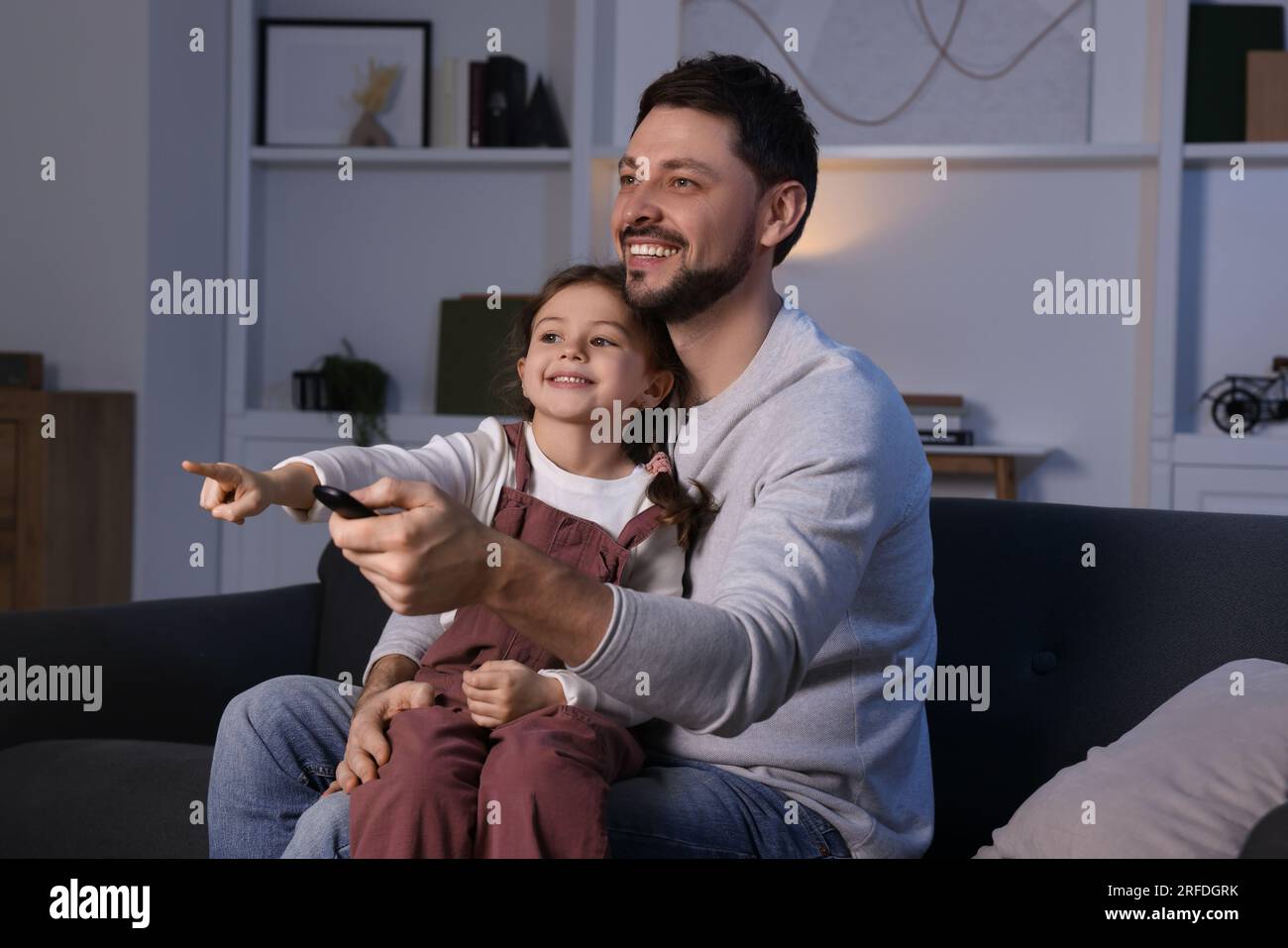 Father and daughter spending time near TV at home. Happy man holding ...