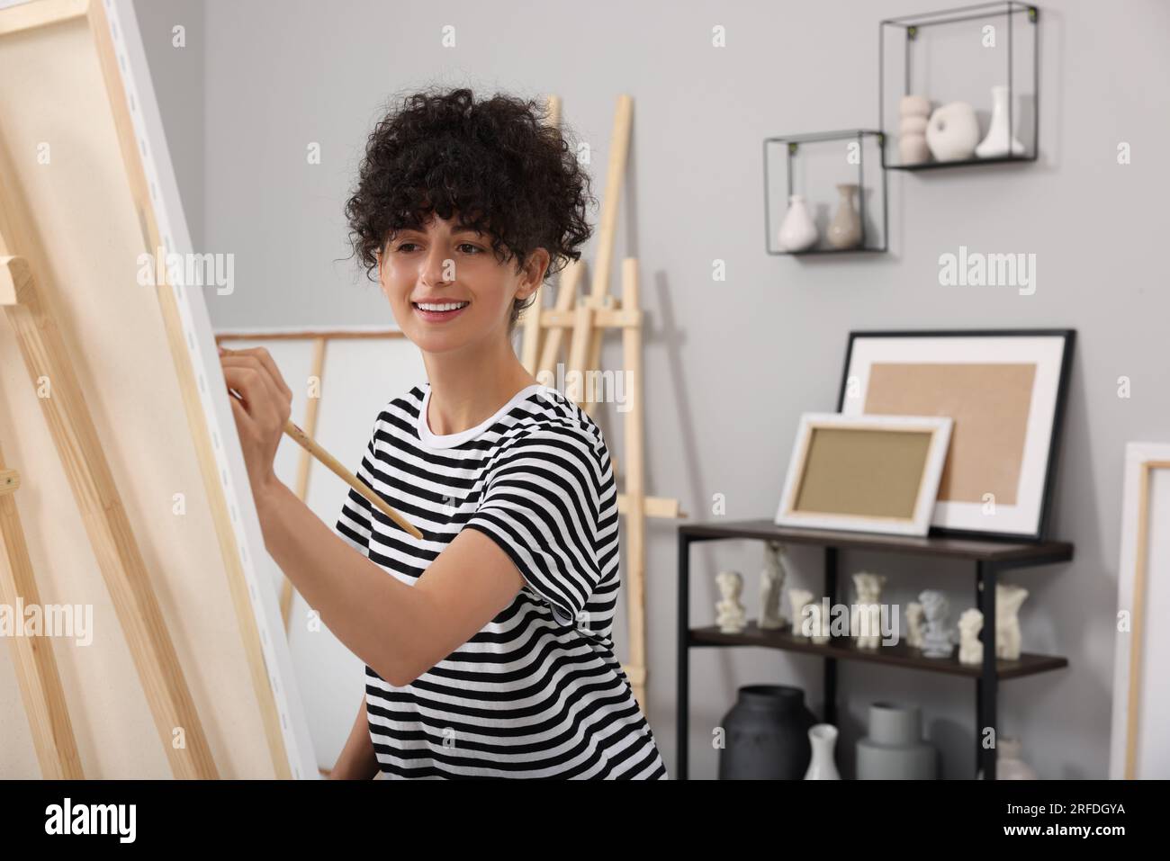 Young woman painting on easel with canvas in studio Stock Photo - Alamy
