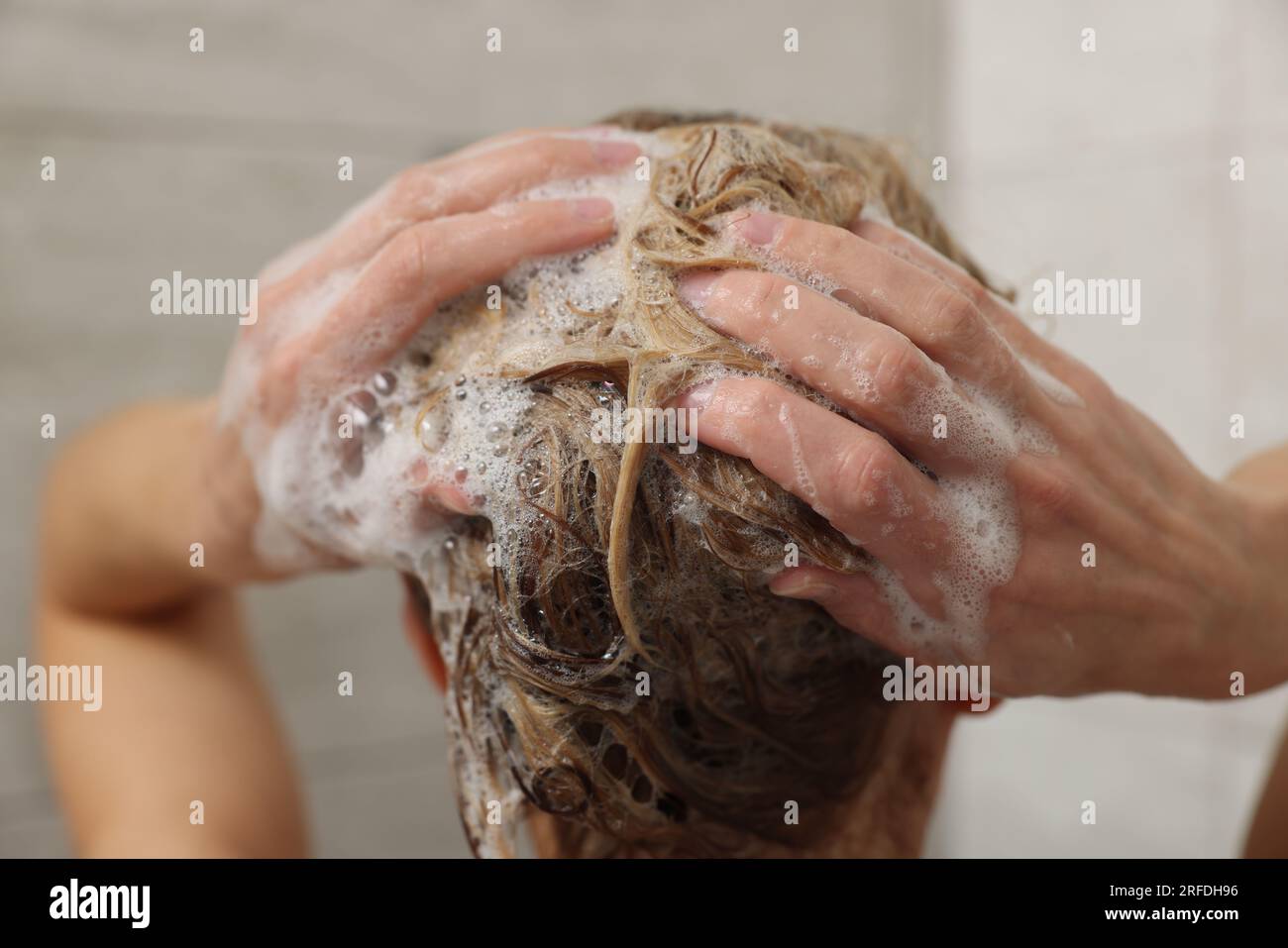 Woman washing hair with shampoo indoors, closeup Stock Photo