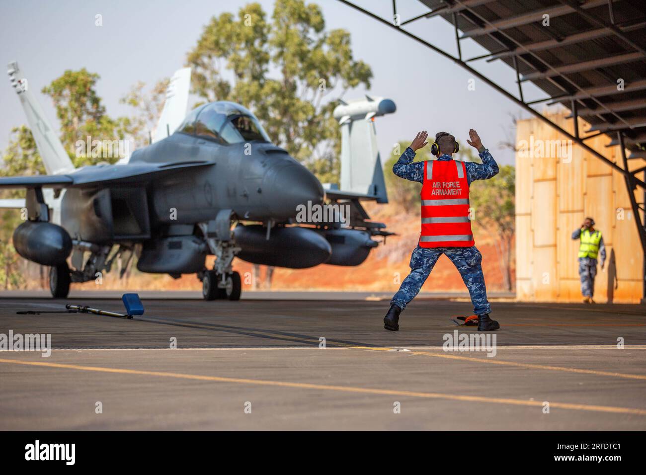 Royal Australian Air Force (RAAF) aircraft technician from No. 6 Squadron, marshals an E/A-18G Growler into an ordnance loading area after a sortie in support of Talisman Sabre 23, at RAAF Base Tindal, Northern Territory, Australia, July 27, 2023. Talisman Sabre is a U.S. Indo-Pacific Command and Australian Defense Forces joint-sponsored exercise that trains in war-fighting scenarios designed to improve U.S. and Australian combat training, readiness and interoperability. (U.S. Air Force photo by 1st Lt. Robert H. Dabbs) Stock Photo