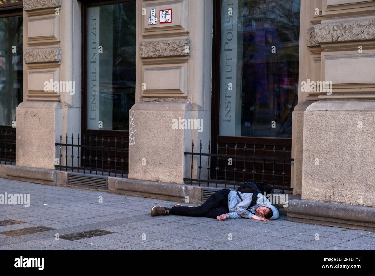 A young man sleeping on the footpath in Budapest, Hungary Stock Photo