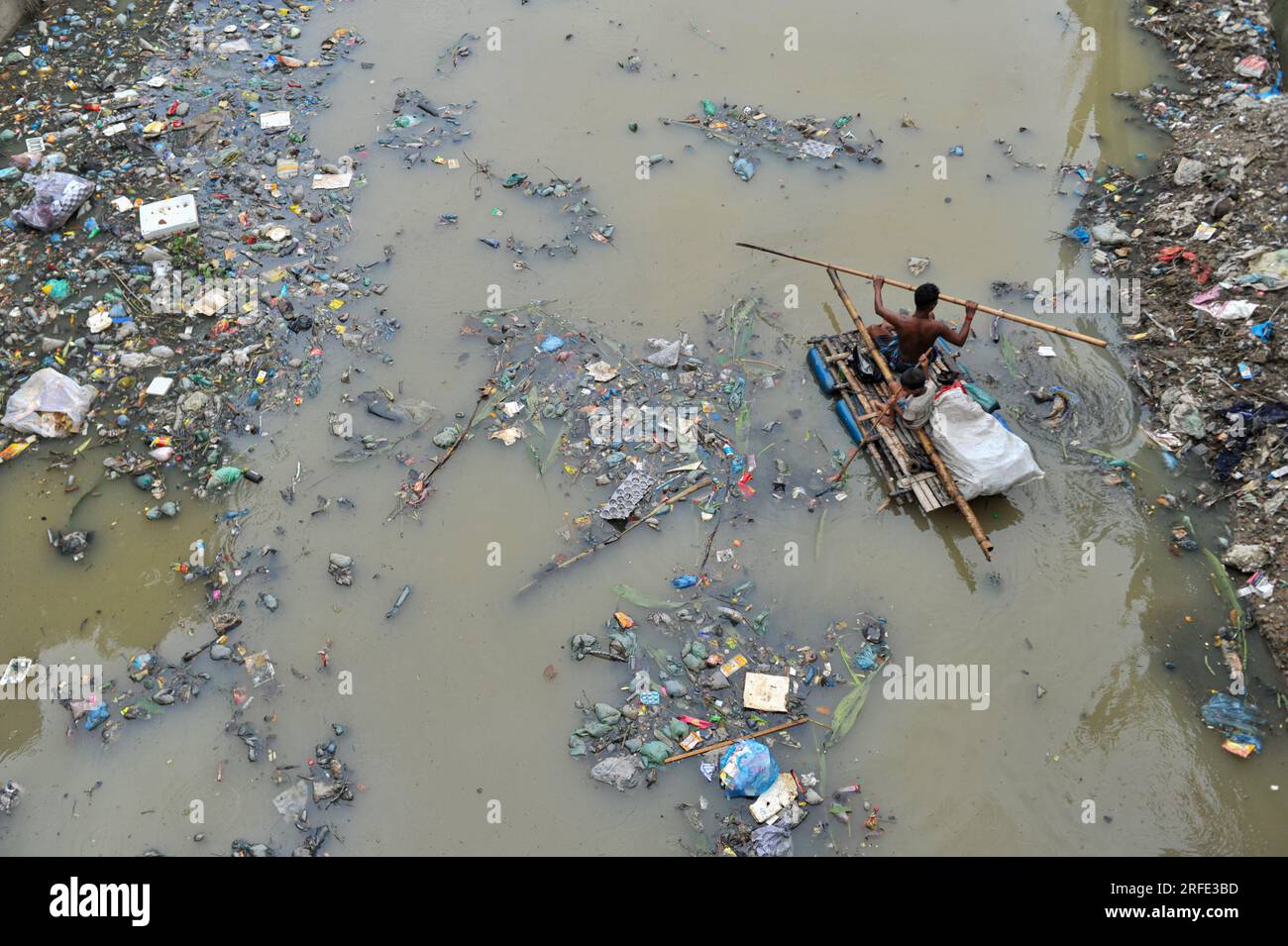 Recycling Raft A father and son are rowing on a hand made raft searching for waste ...