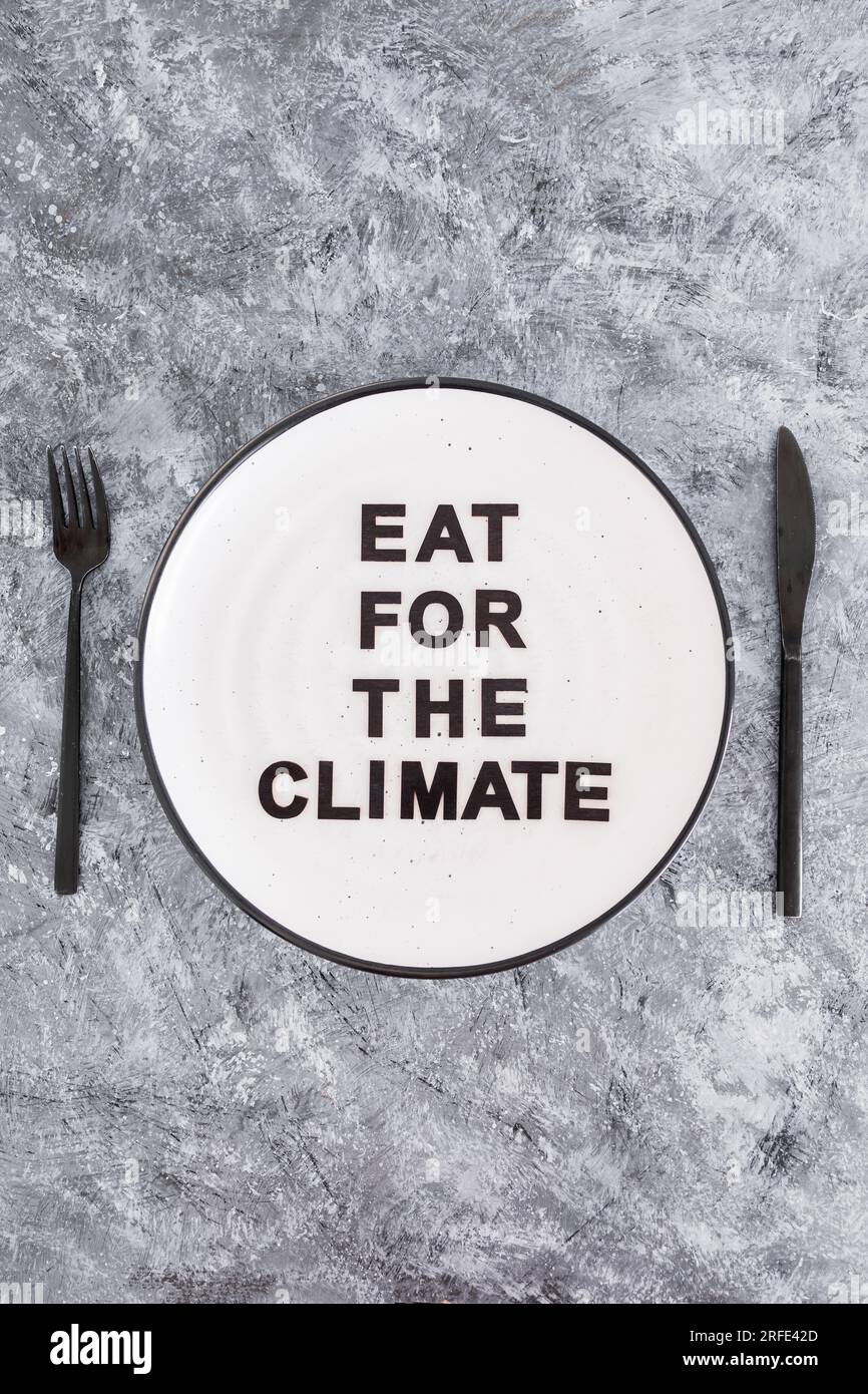 Eat for the climate text on plate with fork and knife, concept of sustainable dietary options Stock Photo