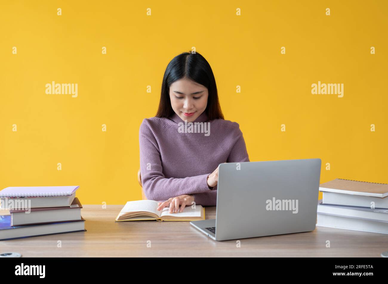A beautiful Asian woman is focusing on reading a book and working on ...