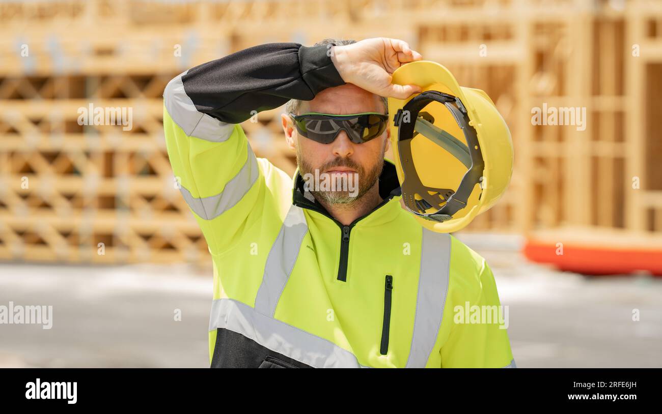 Tired, overworked worker in building uniform on buildings construction ...