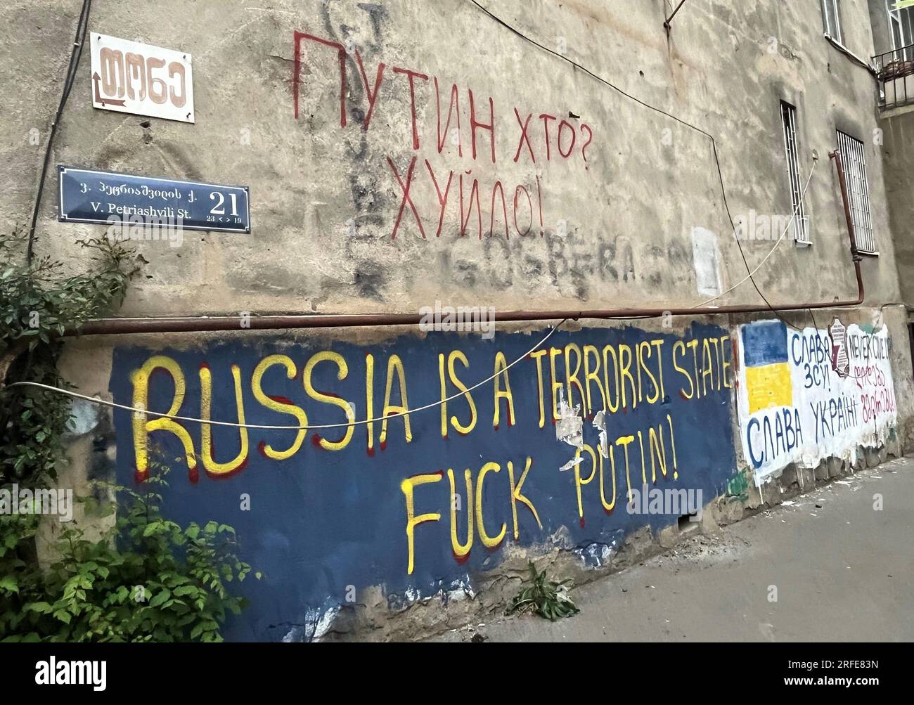 Tiflis, Georgia. 01st May, 2023. On the wall of a house in one of the capital's neighborhoods, anti-Russian slogans are written in English and Ukrainian, condemning Kremlin leader Vladimir Putin's war against Ukraine. Next to it is a blue and yellow flag with the slogan 'Glory to Ukraine.' (To KORR report: 'Georgia rocks between Moscow and EU after war with Russia') Credit: Ulf Mauder/dpa/Alamy Live News Stock Photo