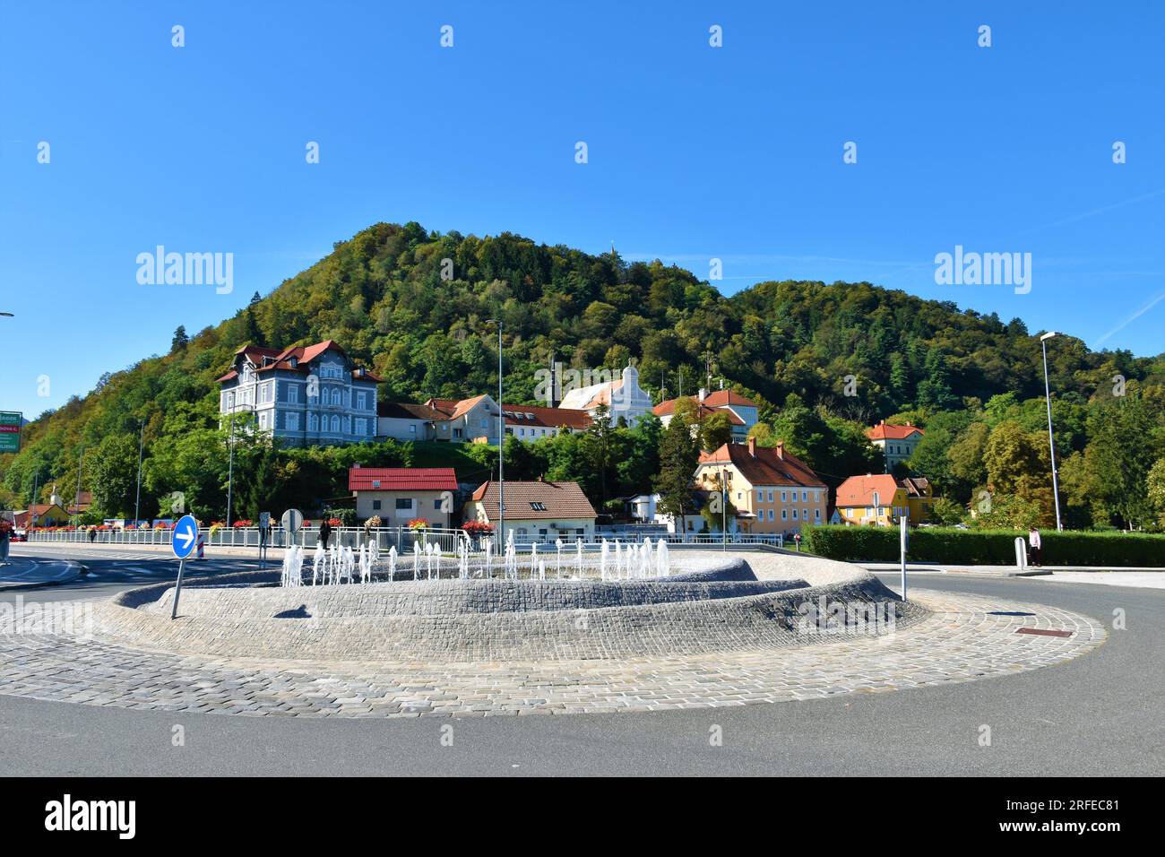 Roundabout with fountain in the middle and Parish of Celje - St. Cecilia at the base of the hill behind in Stajerska, Slovenia Stock Photo
