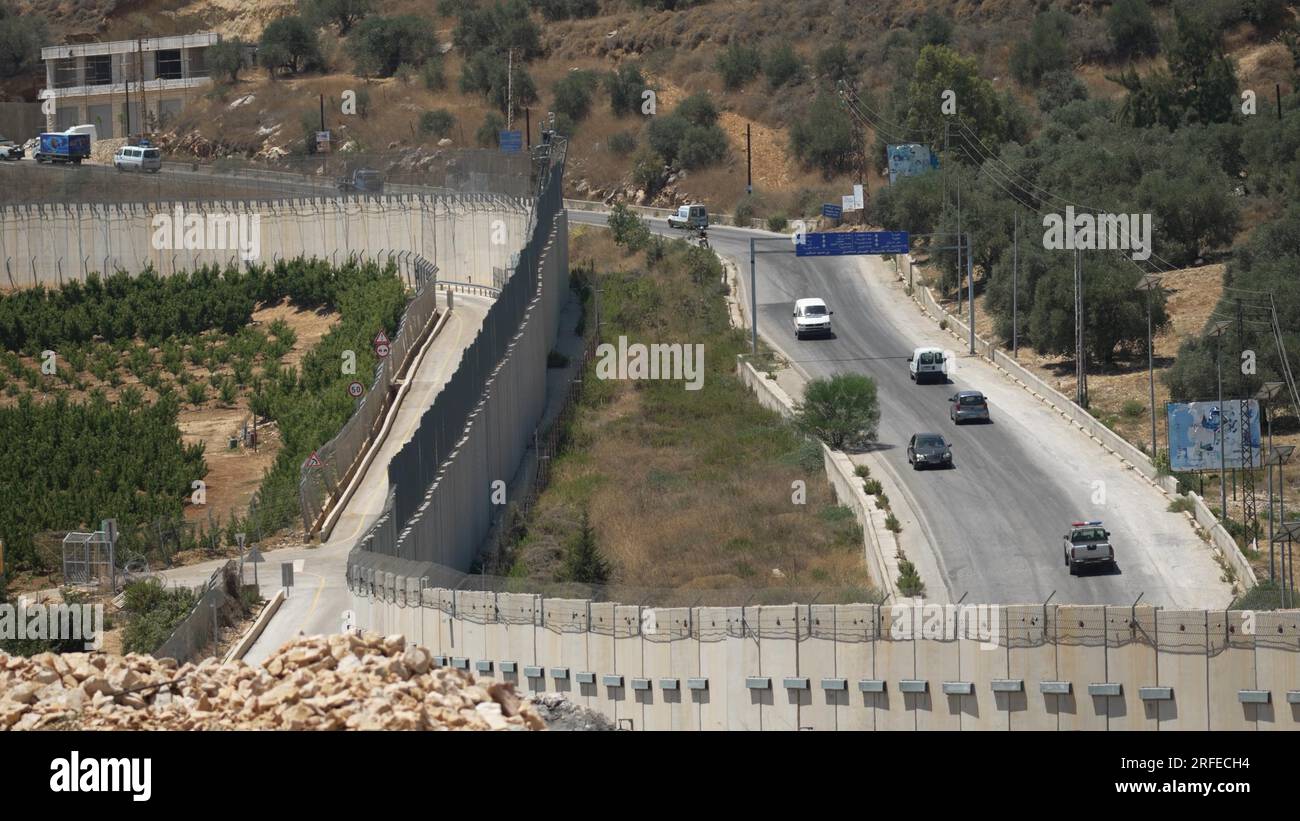 Cars drive along a road in southern Lebanon across the concrete barrier ...