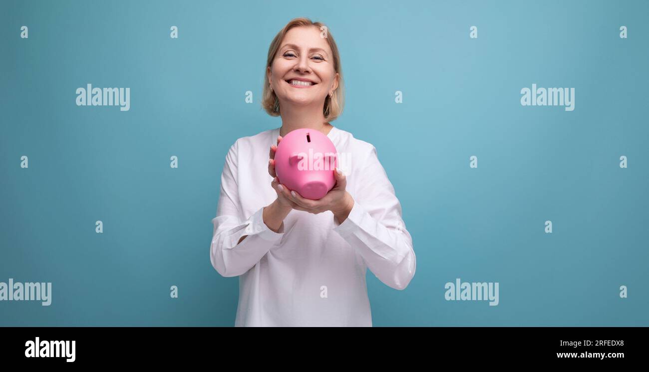 mature woman with blond hair holds savings in a piggy bank Stock Photo ...