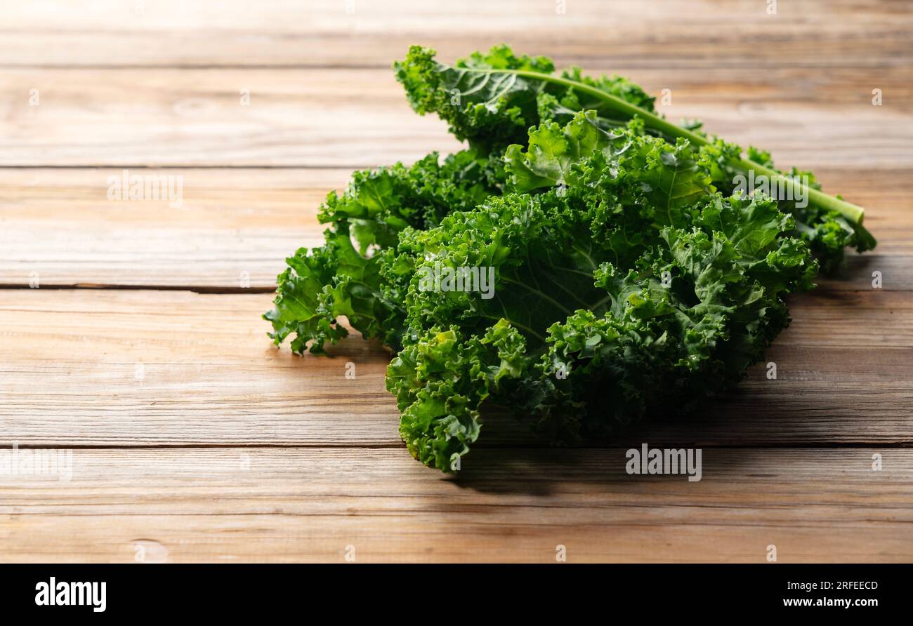 Kale placed against a wooden background. curly kale. Stock Photo