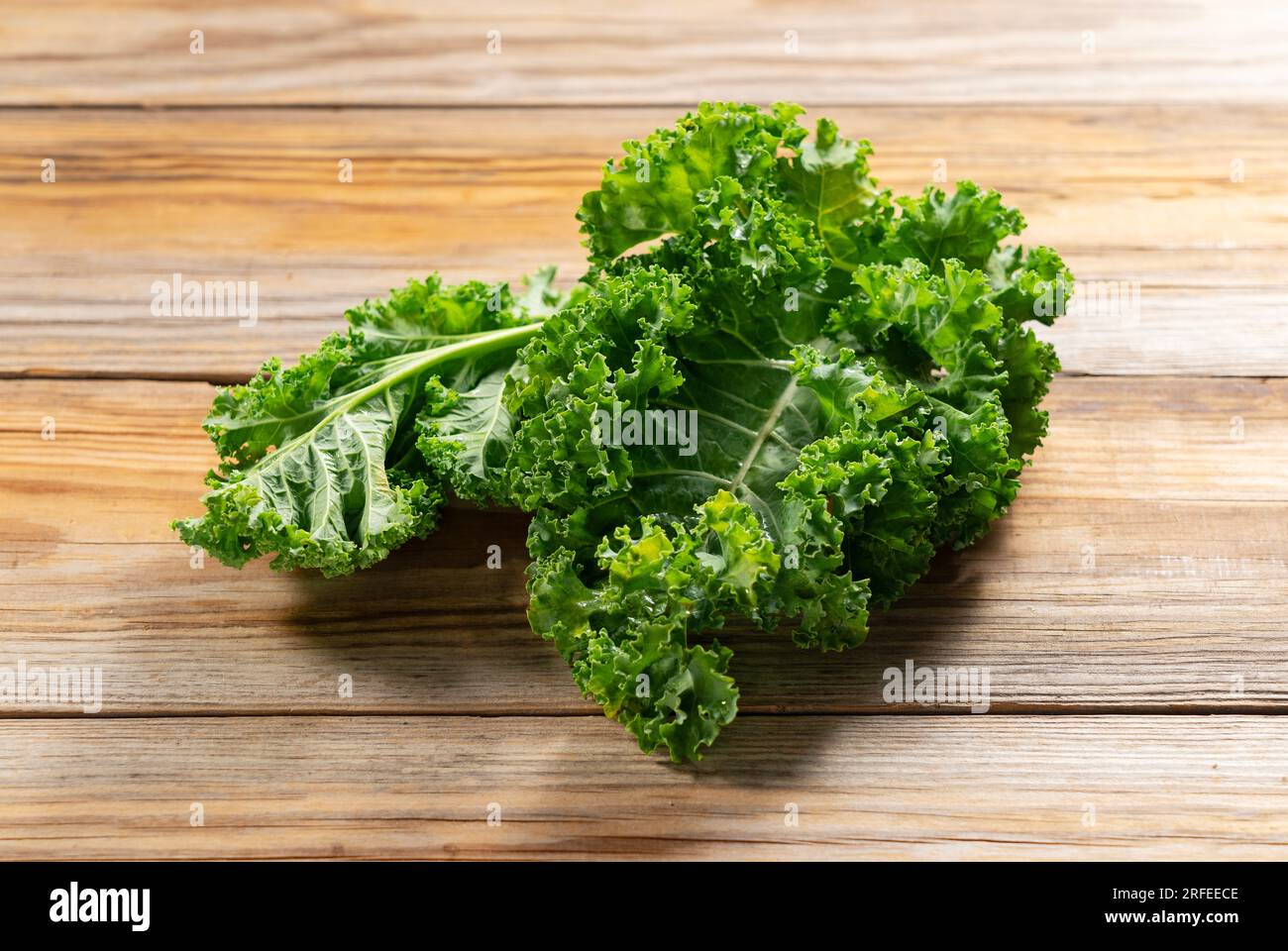 Kale placed against a wooden background. curly kale. Stock Photo