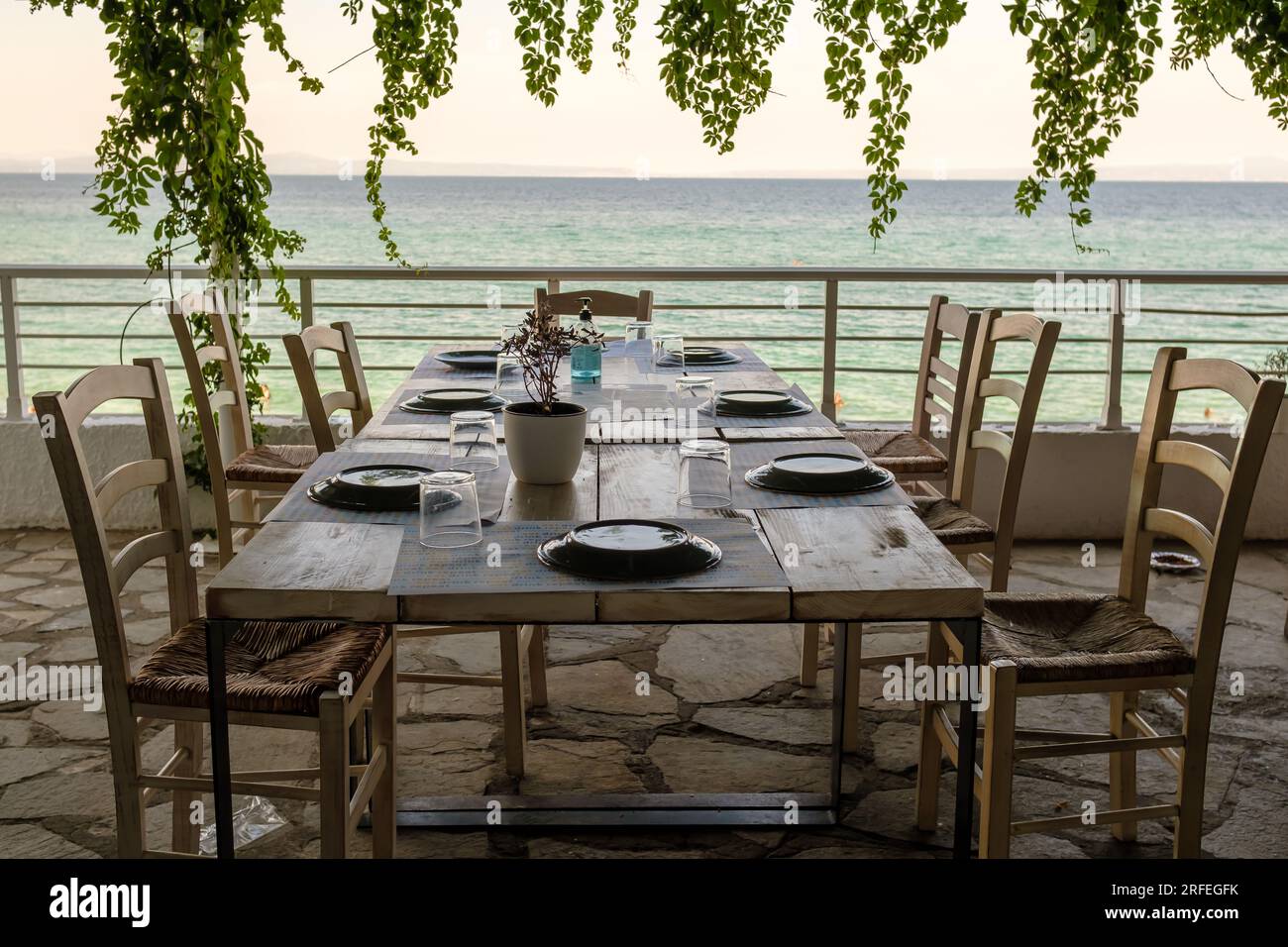 Kriopigi, Greece - August 31, 2022 : View of a beautiful decorated dinner table overlooking the turquoise beach of Kriopigi in Chalkidiki Greece Stock Photo