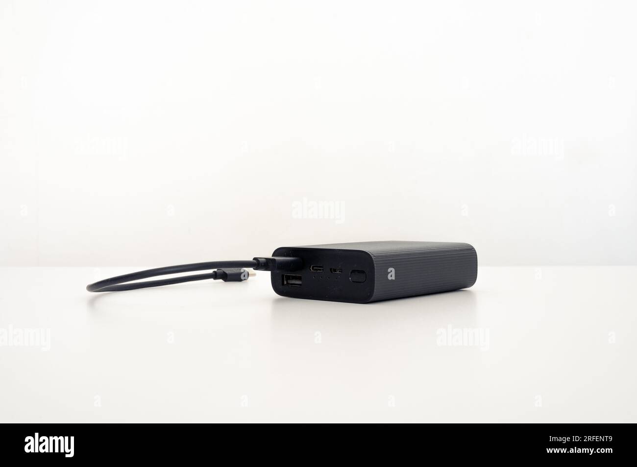 Black mobile charger on the table with one black connected cable: usb type-c. White background. Stock Photo