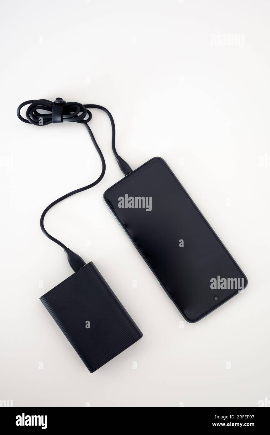 Black power bank charges black mobile phone. Mockup. Black cord cable