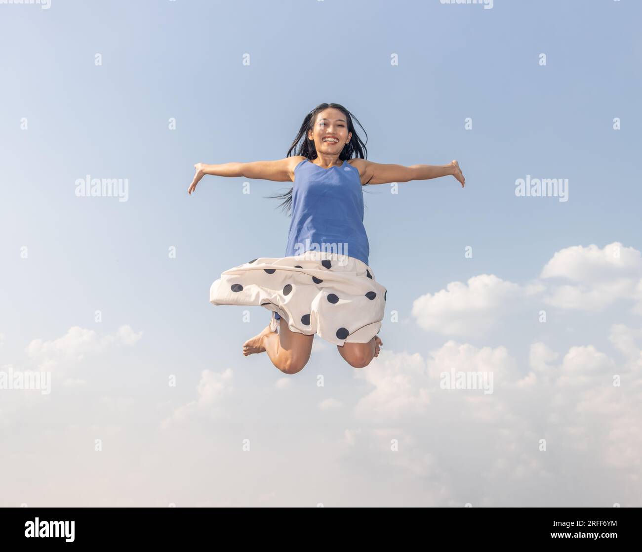 Cheerful woman jumps high on the background of the blue sky Stock Photo