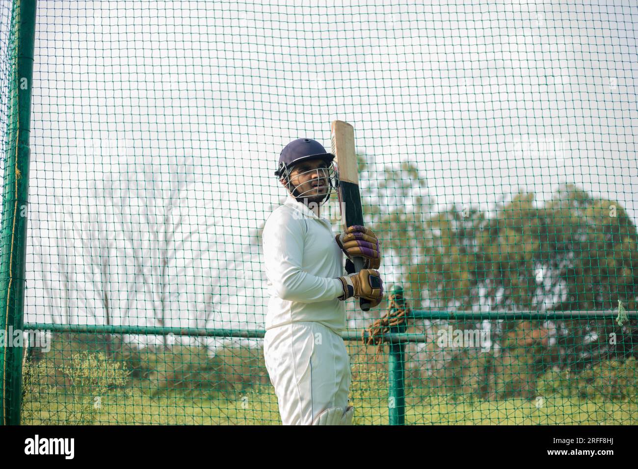 Cricket player is ready to practice batting in the nets during his
