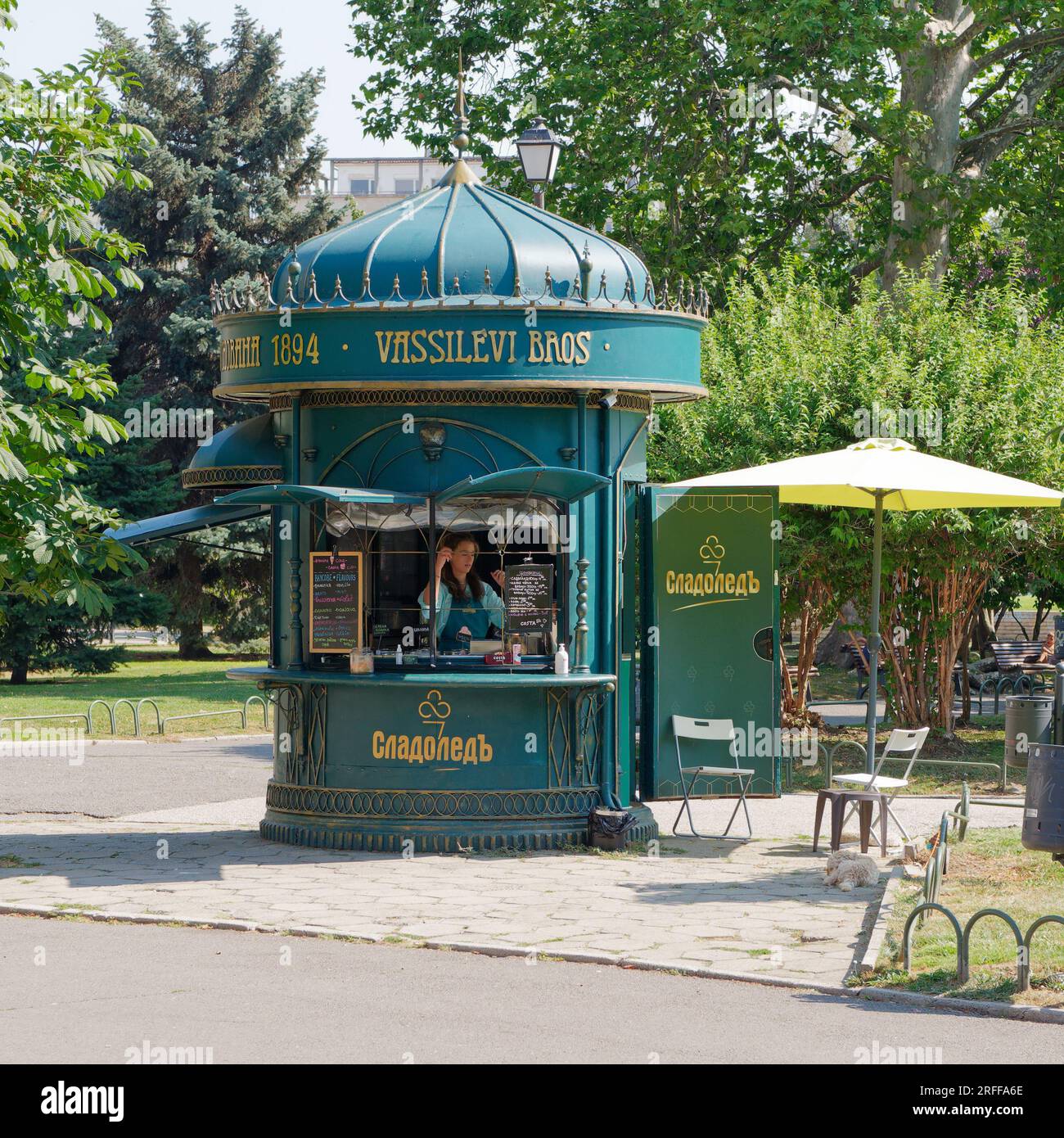 Young woman wearing apron in a Cafe inside a Green Kiosk in the City Garden , in the city of Sofia, Bulgaria. August 3, 2023. Stock Photo