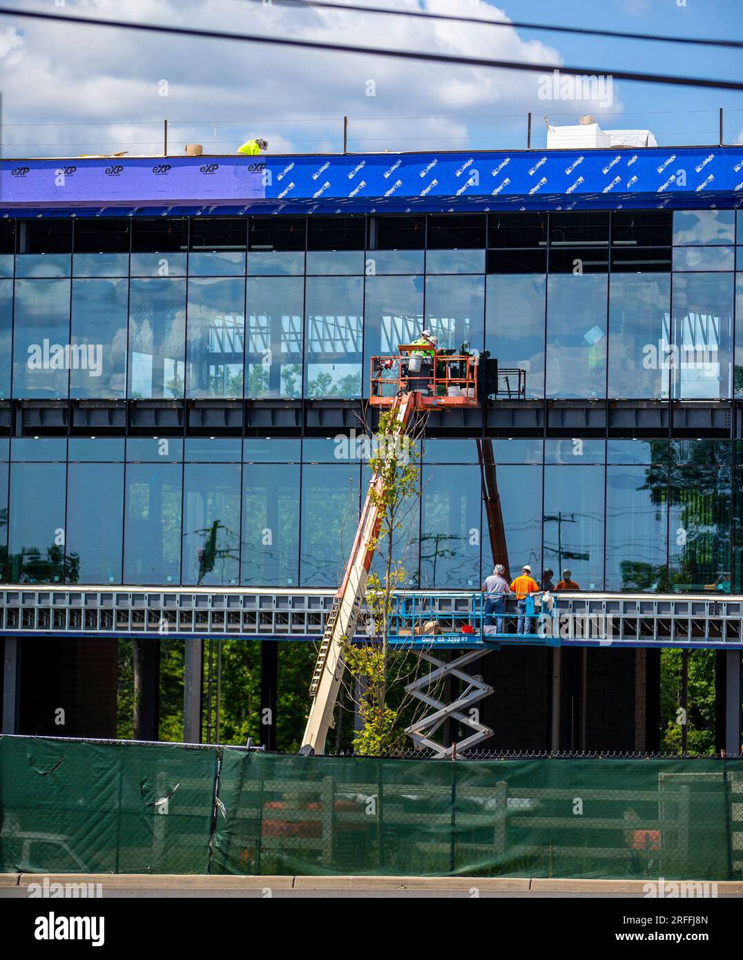 Construction workers installing glass panels on a new office building Stock Photo