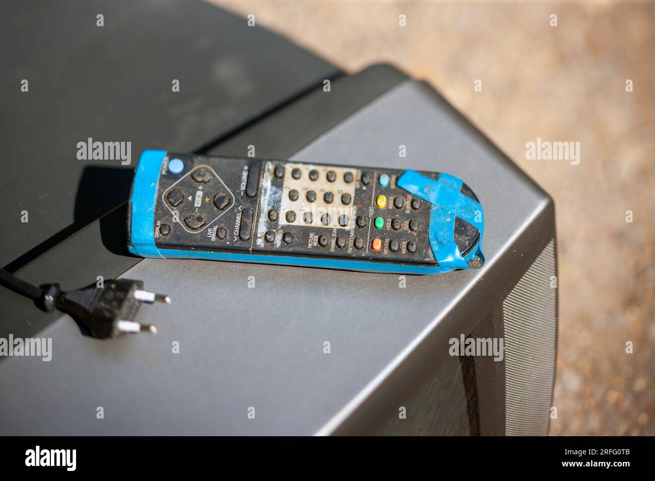 old dirty tv remote , wrapped with adhesive tape and abandoned on discarded tv set Stock Photo