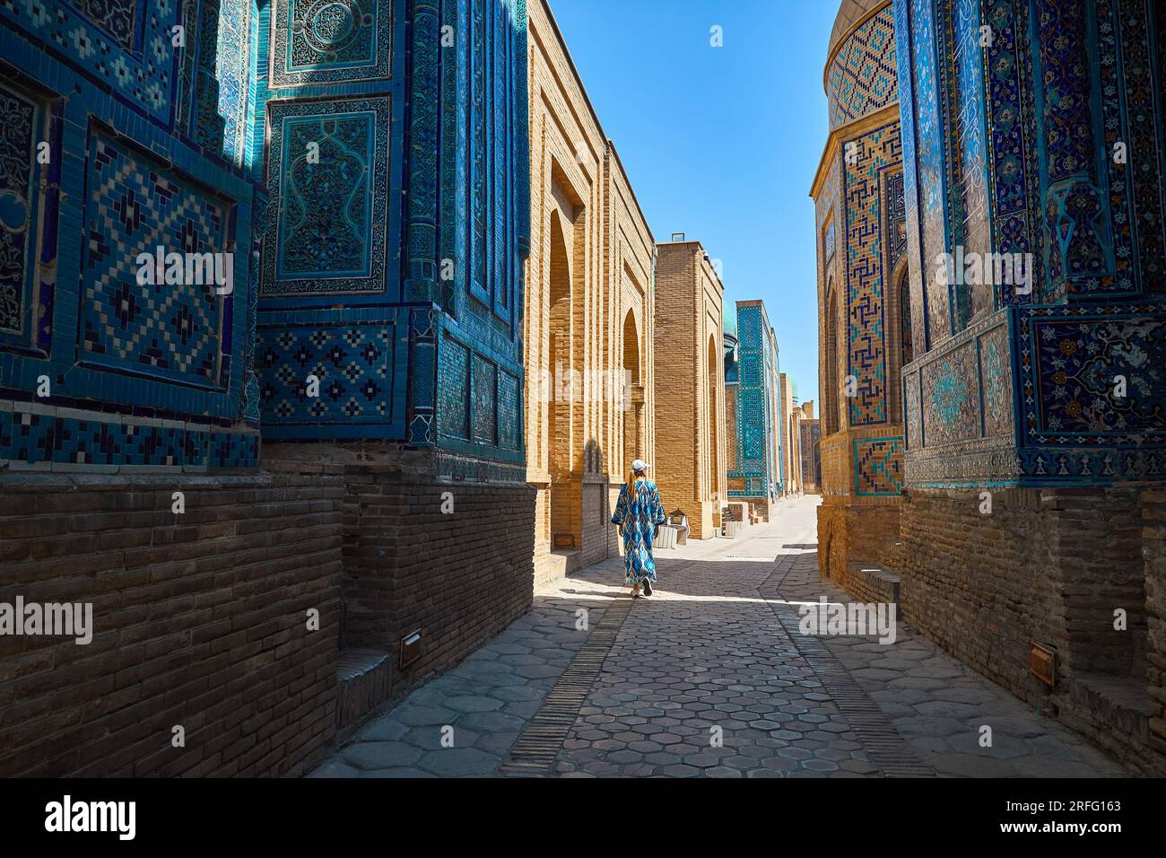 Tourist woman walking in Beautiful Historical cemetery of Shahi Zinda entry Gate with finely decorated by blue and turquoise stone mosaic mausoleums i Stock Photo
