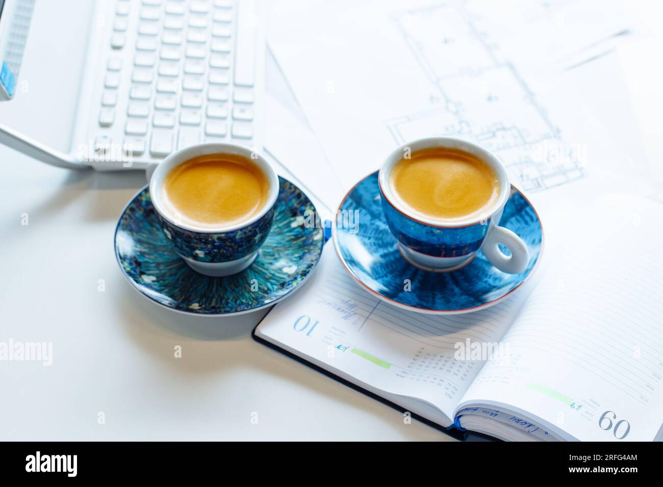 two blue coffee cups, diary, paper building architectural drawing ...