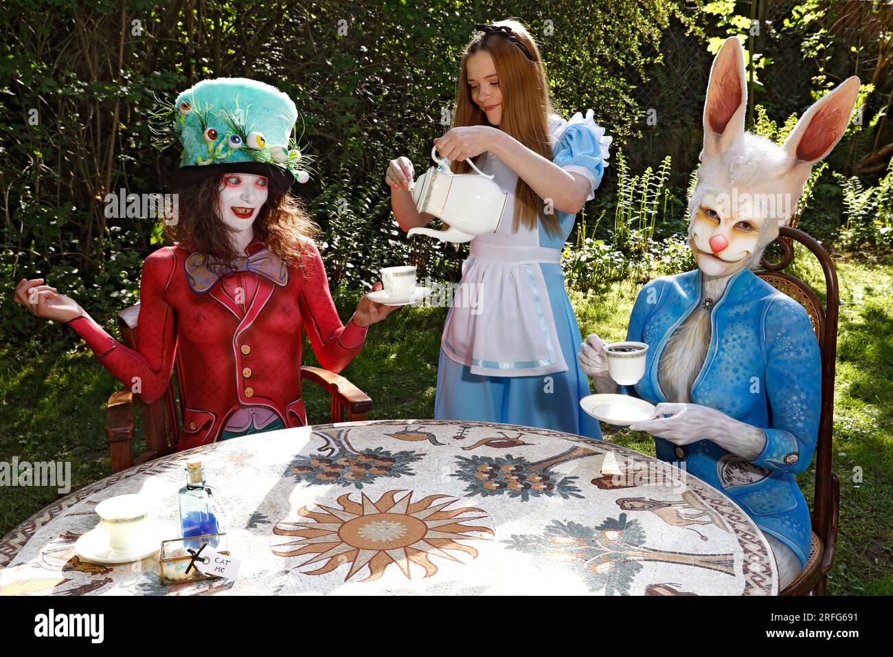 GEEK ART - Bodypainting and Transformaking: Alice in Wonderland photoshooting with Melina as Alice, Julia as the Mad Hatter and Janina as the White Rabbit in the Czarnecki Garden in Hamelin. - A project by photographer Tschiponnique Skupin and bodypainter Enrico Lein Stock Photo