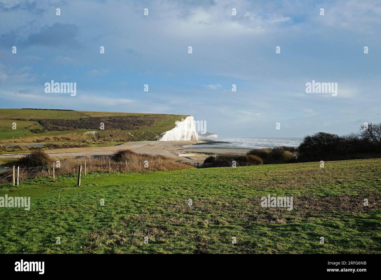 The great views from the top of the Seven Sisters chalk cliffs and national hillsides park with cloudy blue sky - East Sussex, England UK Stock Photo