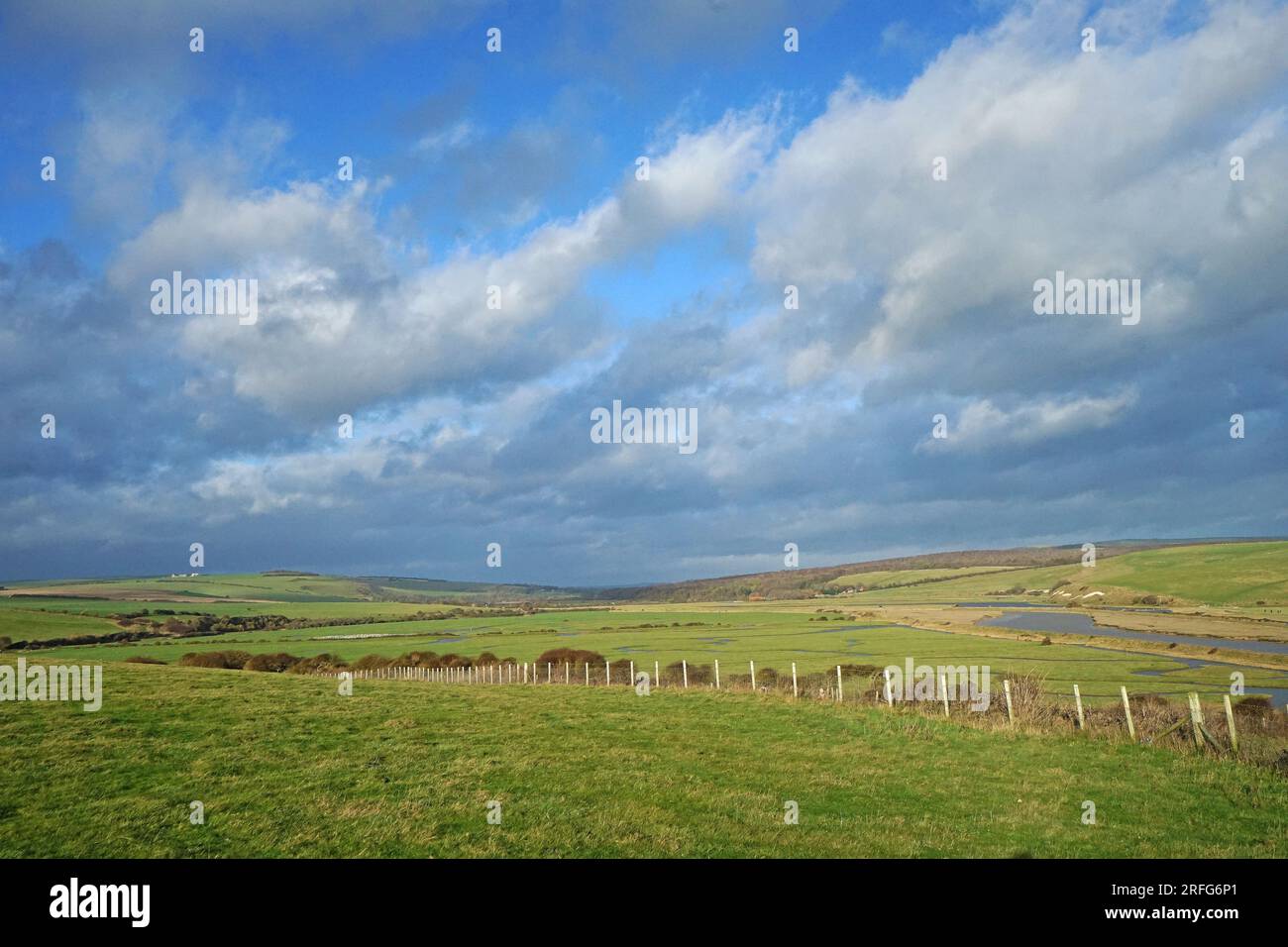 The great views from the top of the Seven Sisters chalk cliffs and national hillsides park with cloudy blue sky - East Sussex, England UK Stock Photo