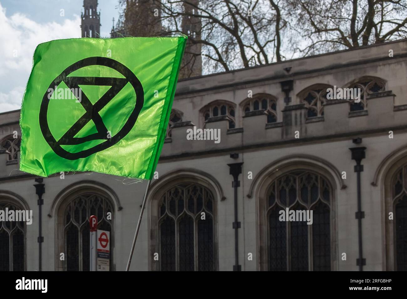 London, UK, 2023. On Earth Day, a green Extinction Rebellion (XR) flag floating in front of Saint Margaret's Church, on Broad Sanctuary Stock Photo