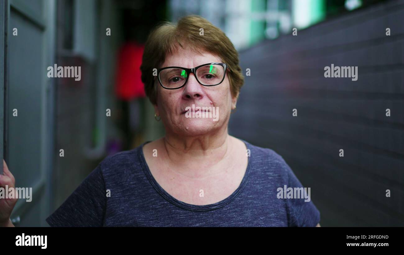 Portrait of a serious elderly woman looking at camera standing in ...