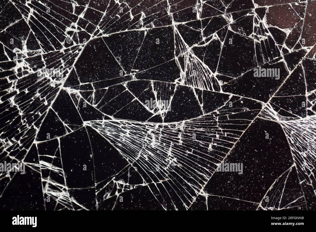 broken dirty glass with lots of damage and cracks on a black background ...