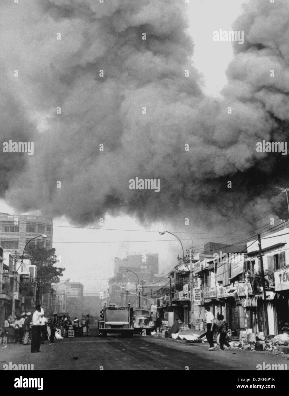 SAIGON, VIETNAM - circa 31 January 1968 - Black smoke covers areas of the capital city and fire trucks rush to the scenes of fires set during attacks Stock Photo