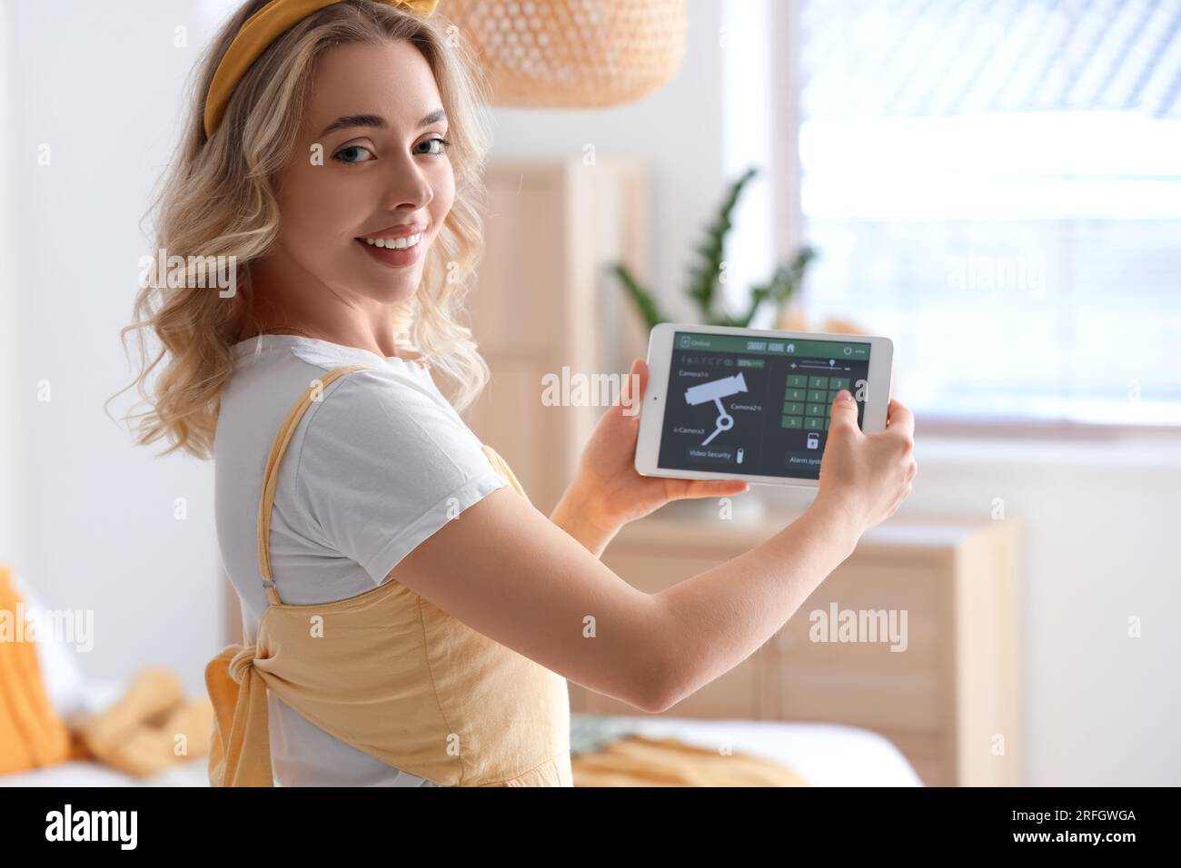 Young woman with smart home security system control panel in bedroom ...