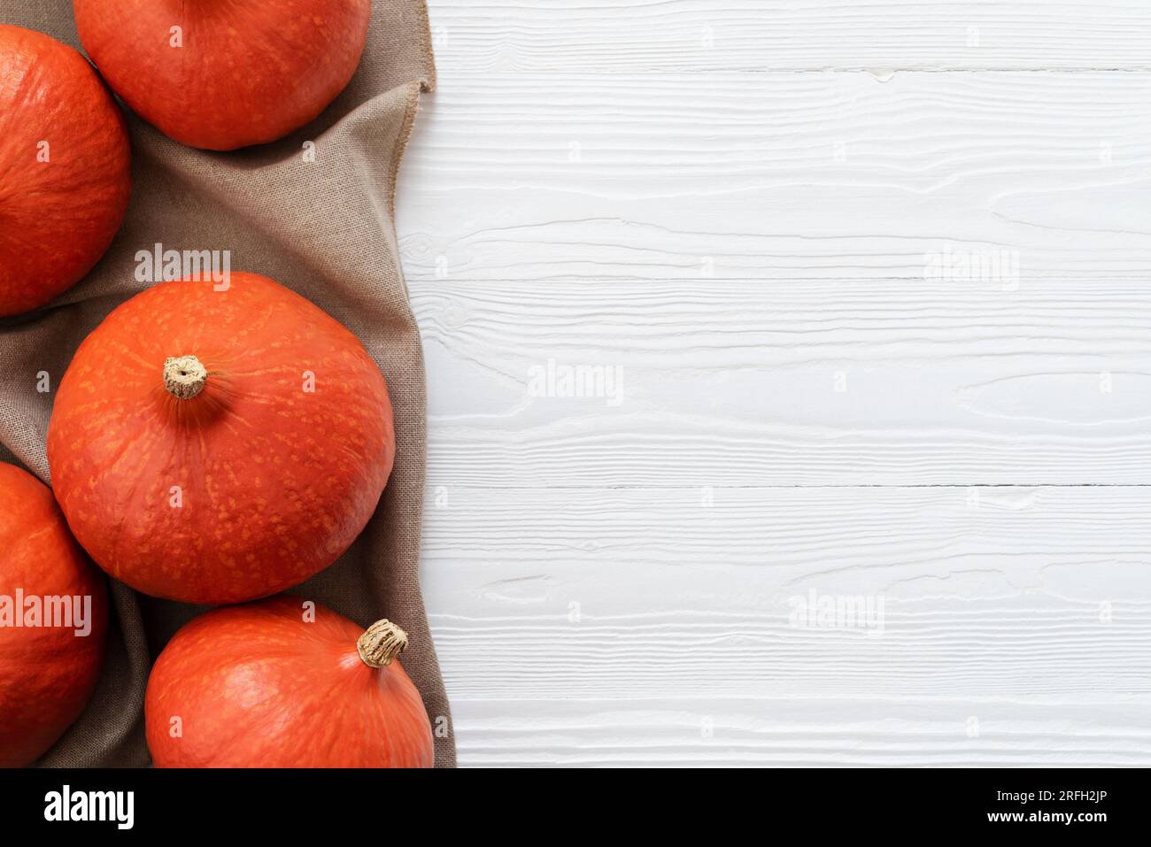 White Wooden Background with a Harvest of Red Kuri Squash and Copy Space Stock Photo