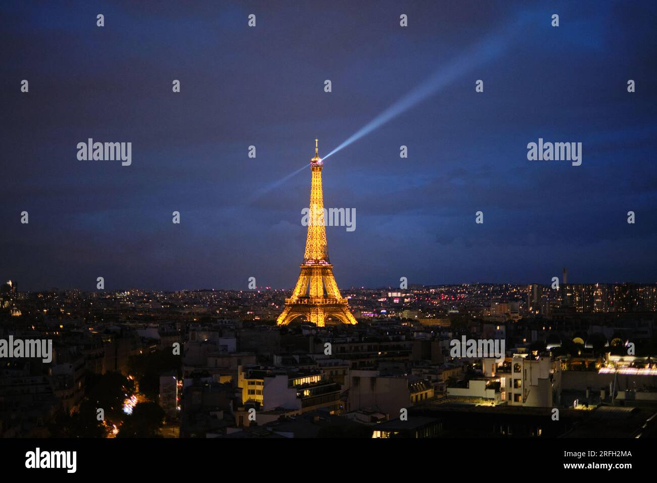 The Eiffel Tower lit up at night with the rotating beacon at the top over the city of Paris Stock Photo