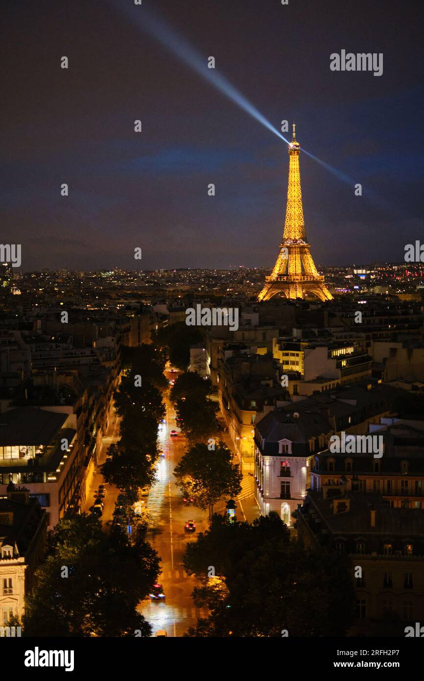 The Eiffel Tower lit up at night with the rotating beacon at the top