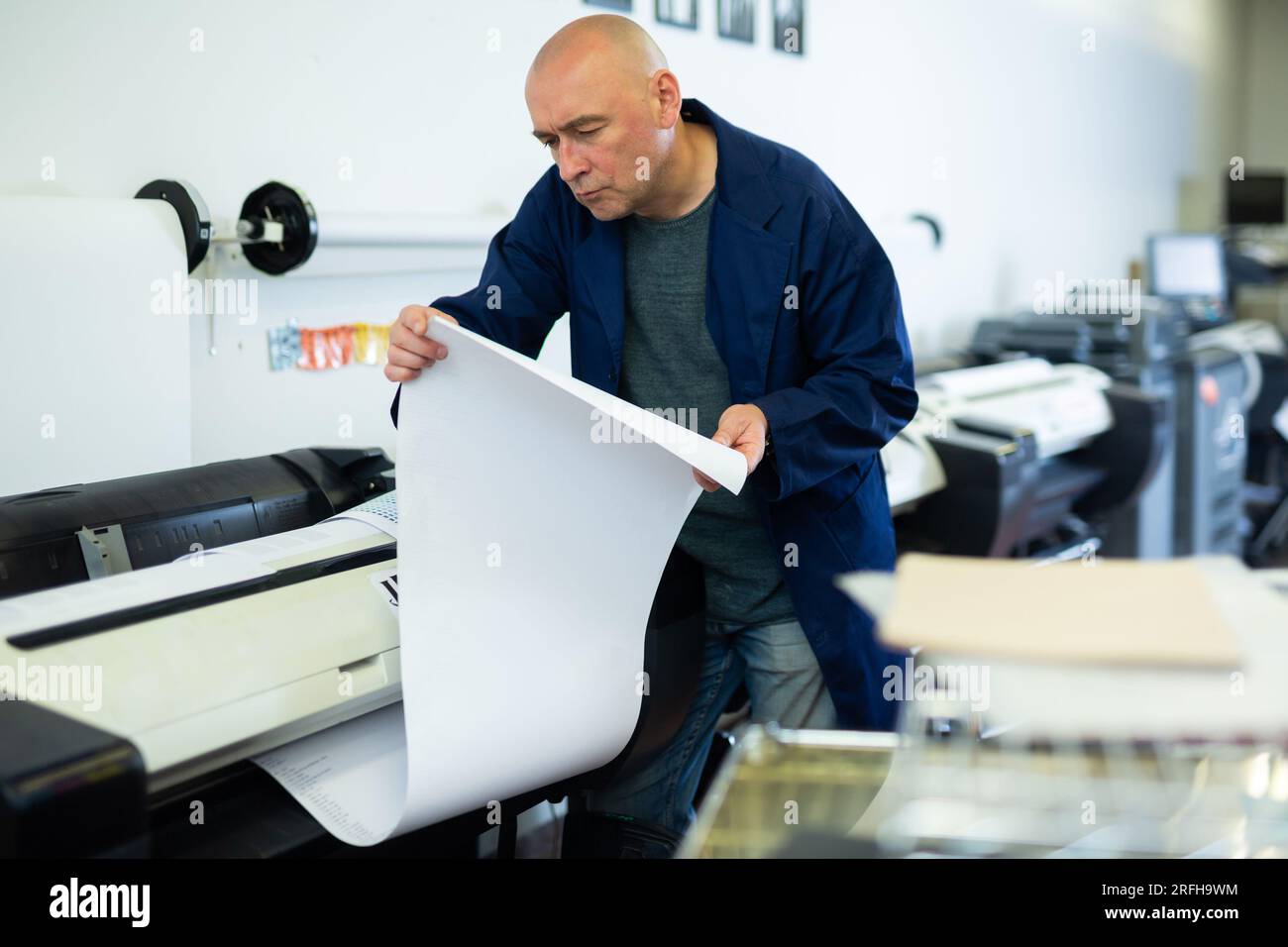 Service man uses plotter and checks functionality in printing shop Stock Photo