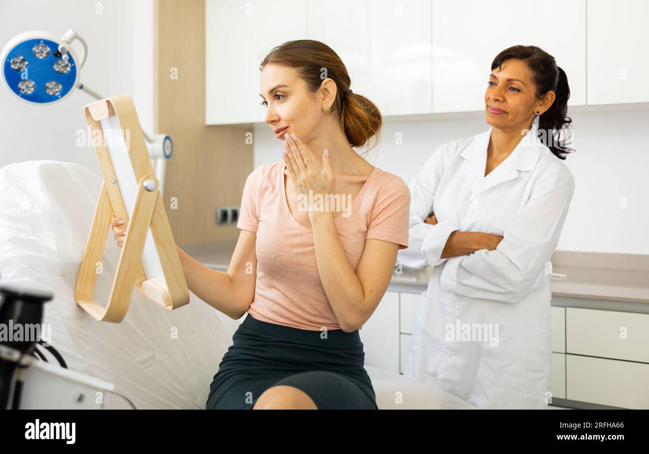 Woman looking in mirror after cosmetology procedure Stock Photo