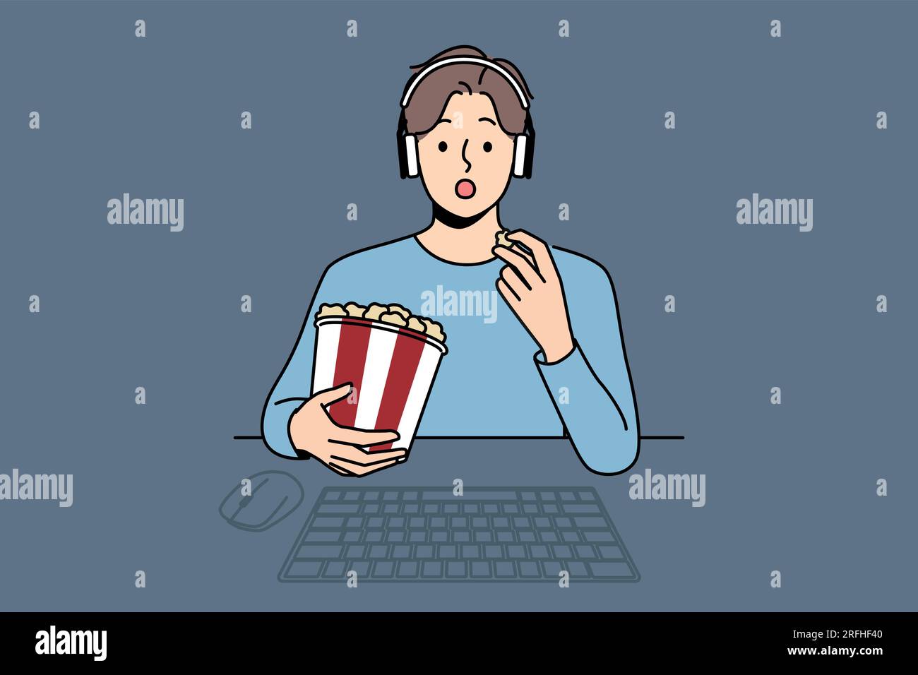 Man with package of popcorn watches movie sitting at table with