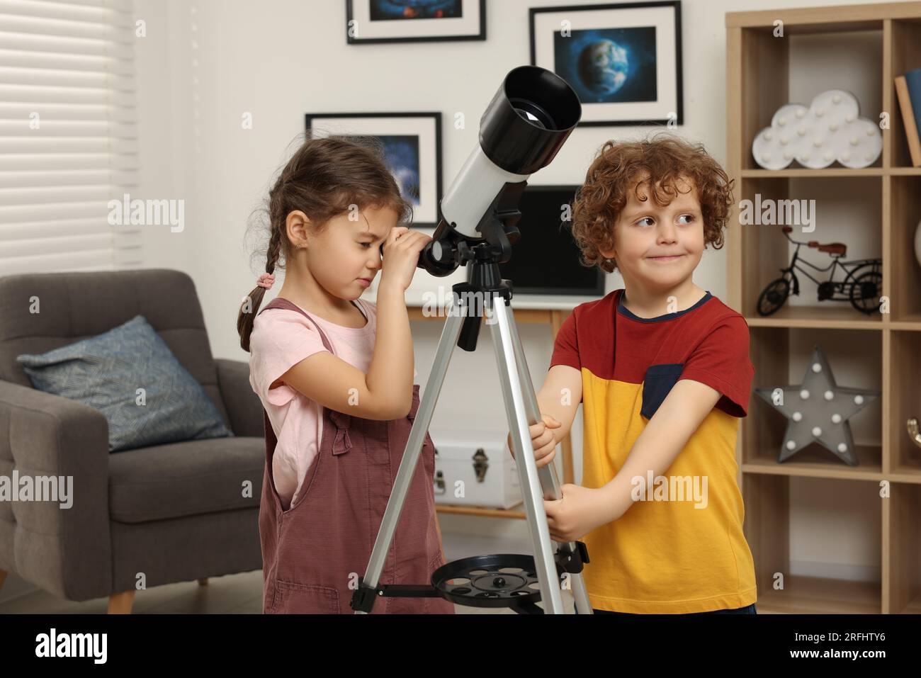 Cute little children using telescope to look at stars in room Stock