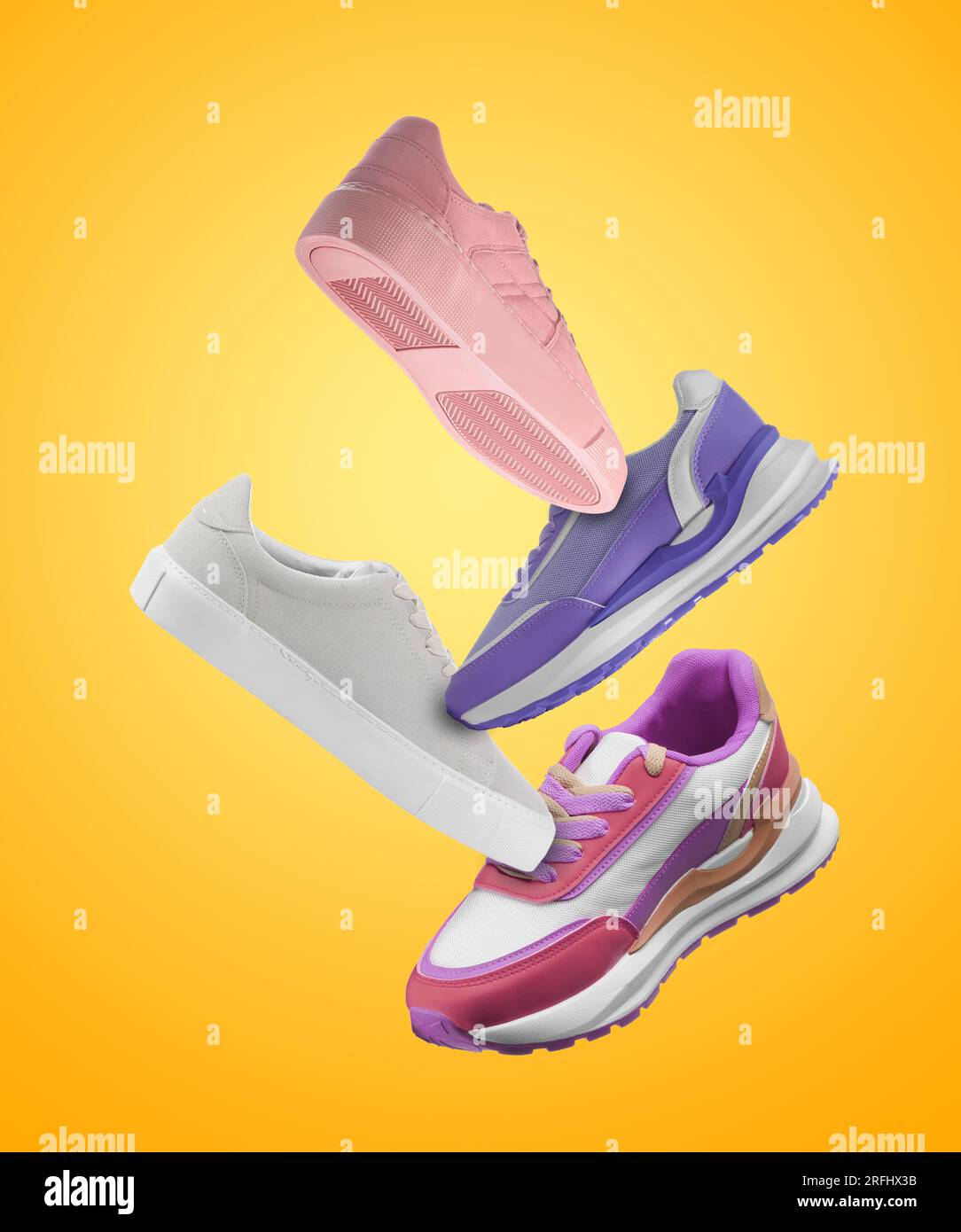 Different sneakers falling on orange gradient background Stock