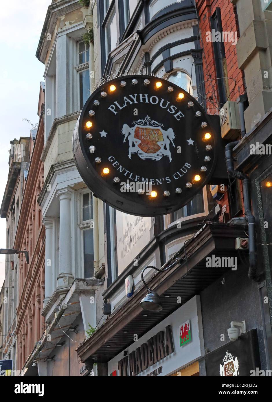 Illuminated circular sign for Playhouse Gentlemen’s Club mounted on the exterior of a building in Cardiff city centre, Wales, UK. Night time economy Stock Photo