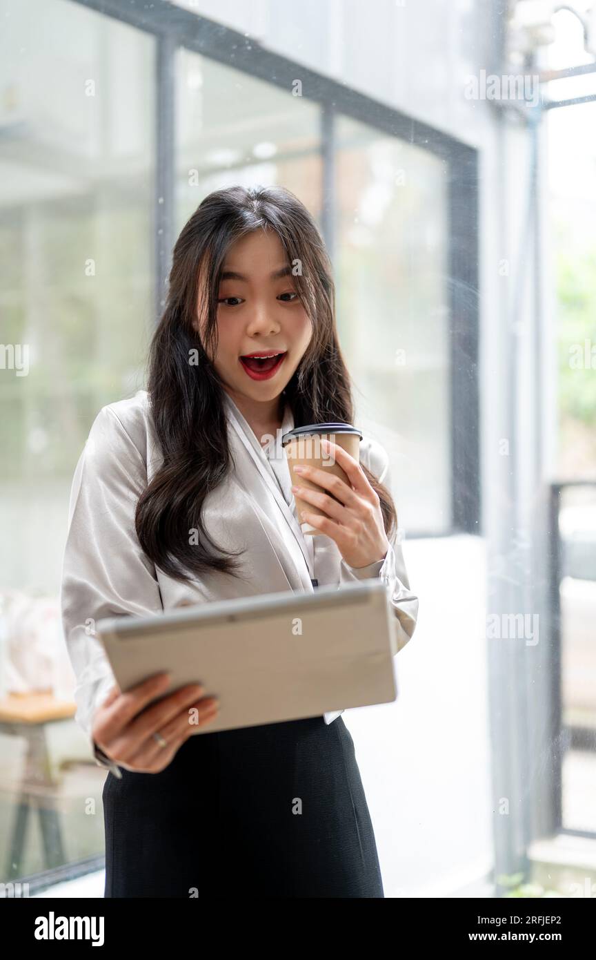A portrait of a beautiful Asian businesswoman is looking at her tablet ...