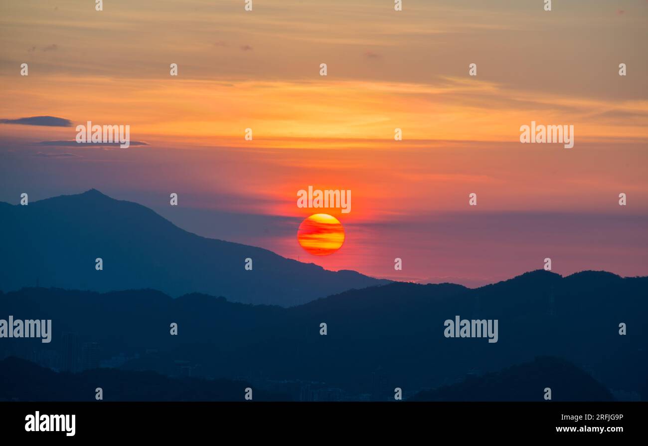 The orangered sunset is covered by clouds as it moves towards the