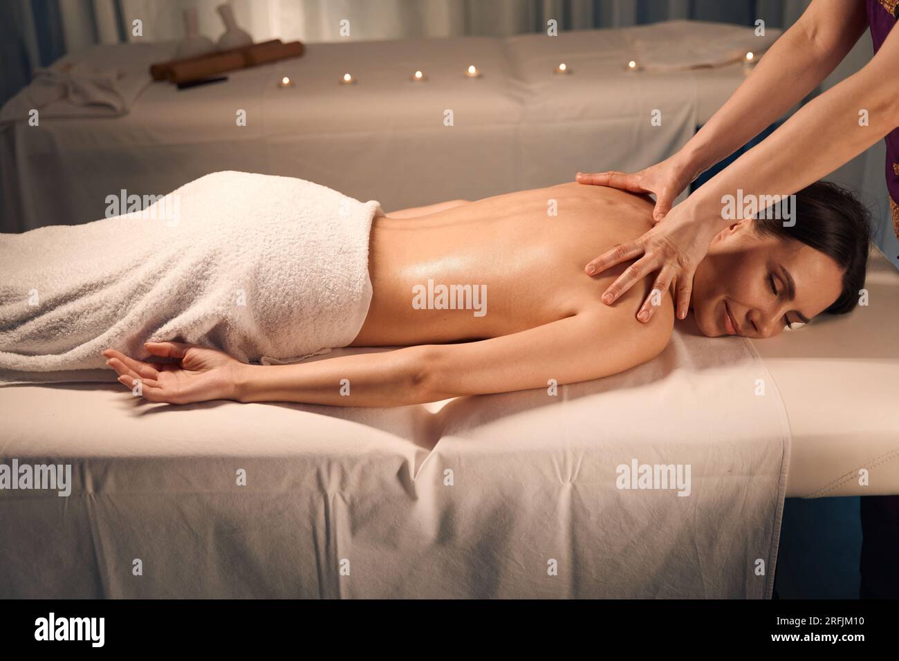 experienced-masseuse-giving-upper-back-massage-to-female-stock-photo
